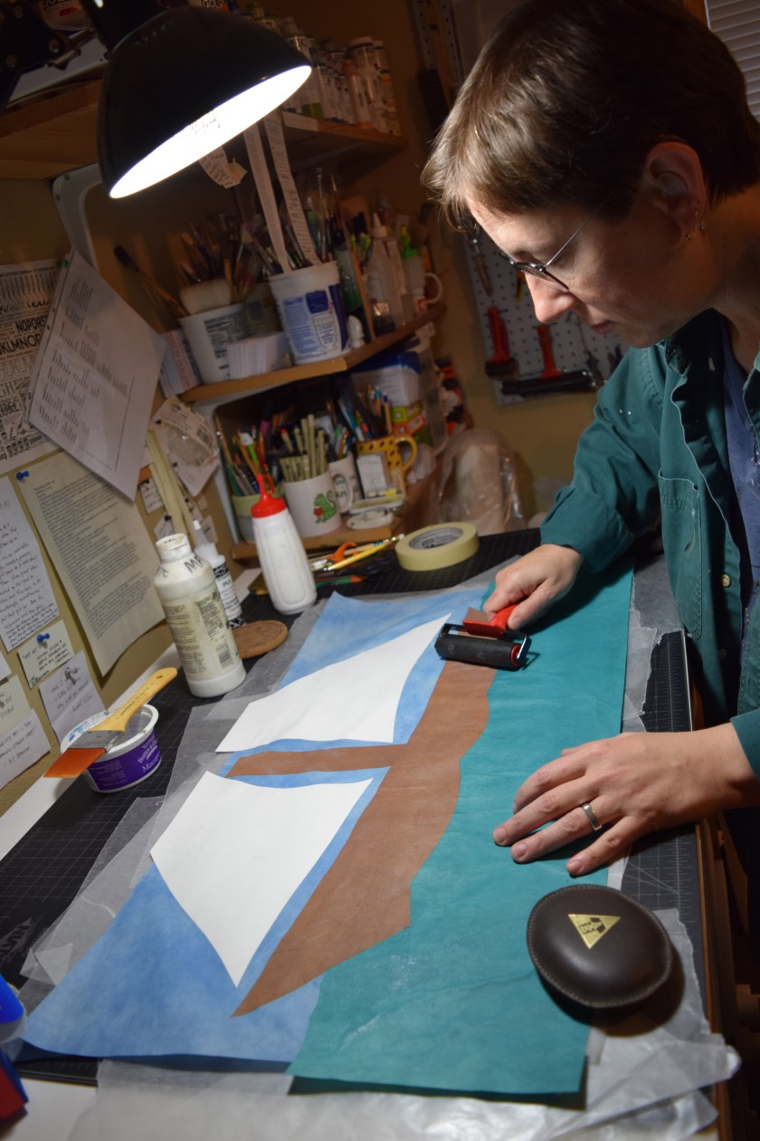 Cut paper shapes have glue on them and are being "rolled" flat