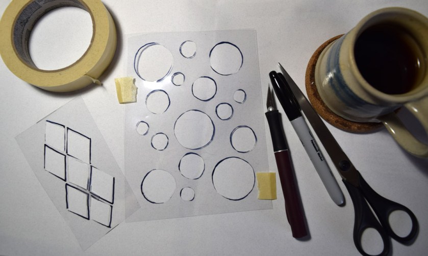 Sue Clancy's work table full of tools for cutting stencils and the stencils she cut. Oh, and her cup of coffee.